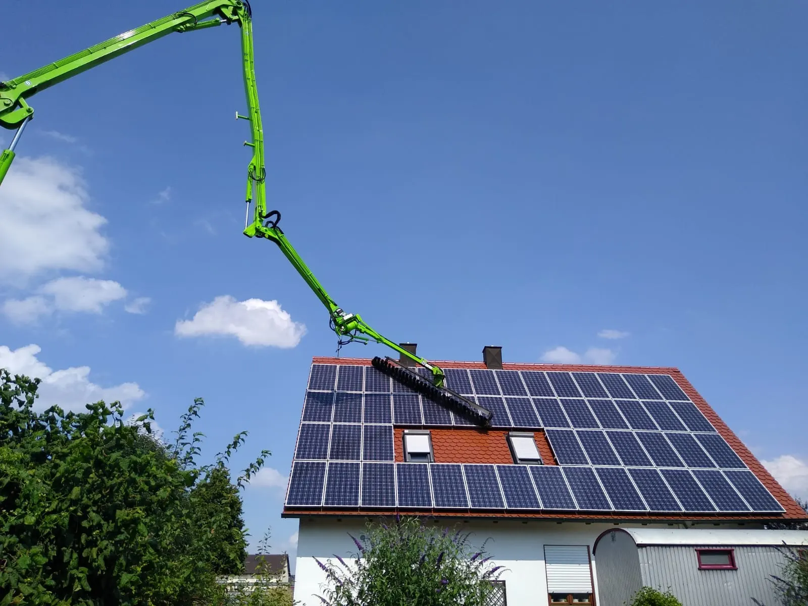 Rotierende Bürste reinigt PV-Module mit Wasser auf einem Hallendach
